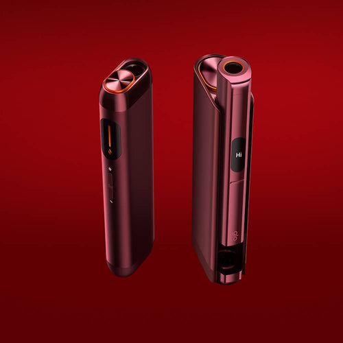 Two sleek, metallic red electronic devices stand on a matching red background. Both devices have rounded edges, a circular top opening, side buttons, and a small screen displaying the word Hi.